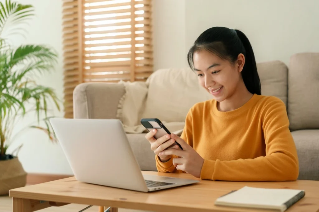 Woman using mobile phone and laptop to contact Educate Future